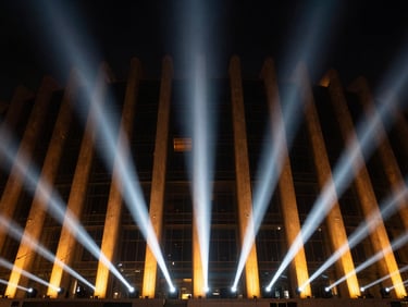 Dramatic wide angle night photography of a modern architectural facade in Al Khobar, illuminated with sharp amber and cool-white directional light beams, reflecting off steel and glass, high-contrast, medium format
