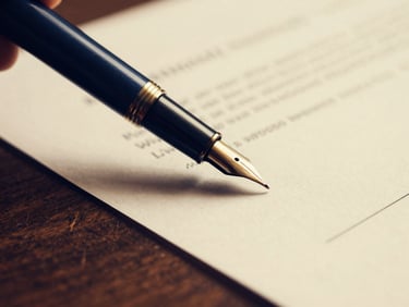 Macro close-up of a fountain pen signing a medical-legal document on a dark wooden desk, warm golden lighting, shallow depth of field, 35mm