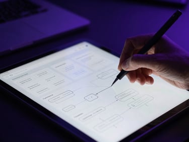 Close-up of hands sketching user flows on a tablet, high-fidelity UI/UX mockups on screen, moody studio lighting with purple backlighting, high contrast, cinematic depth of field, 35mm