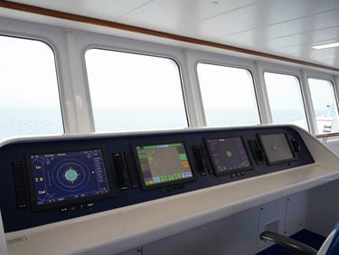 Crisp editorial shot of a cruise ship bridge, modern navigation screens glowing softly, bright maritime daylight through wide windows