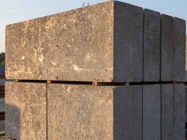 Close-up of dense AAC structural blocks stacked two courses high on a construction site, block edges in focus, early morning golden light raking across surface texture