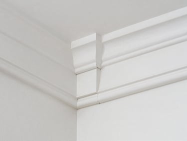 Close-up of a perfectly installed white crown molding joint, showing tight miter and clean lines, bright natural light.