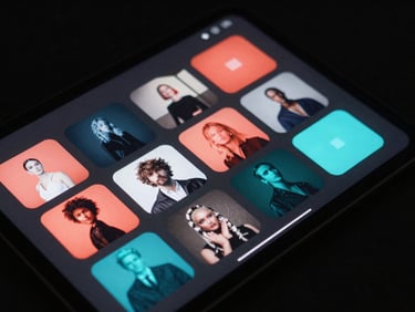 Angled perspective of a tablet screen displaying a clean grid of media assets, deep charcoal interface with subtle cyan highlights