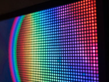 Macro detail shot of a bezel-free pixel video wall, vibrant LED pixel arrays in sharp focus under dark ambient lighting, 50mm lens