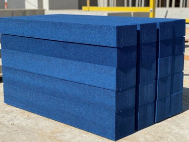 Extruded polystyrene blue foam insulation boards stacked neatly on an active Egyptian construction site, bright daylight, concrete textures, sharp focus