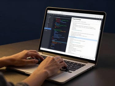 Hands typing on a premium laptop, displaying a clean code editor and marketing metrics, warm studio lighting