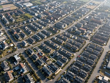 High-angle aerial orthomosaic map of a residential township development under bright morning sun, showing clean parcel boundaries, road layouts, and digital surveying grid overlays.