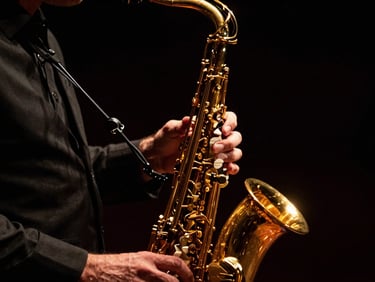 Cinematic close-up of Stéphane Nerplat's hands playing a golden saxophone, dramatic low-key lighting, warm golden highlights, deep black background, shallow depth of field, 35mm