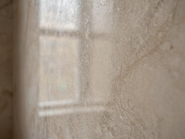 Close-up of a burnished Venetian plaster finish with marble-like depth in natural stone color, high gloss, soft light.