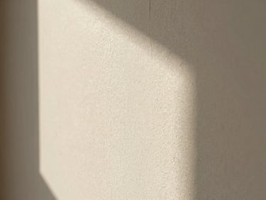 Close-up of a limewash wall texture in warm off-white, soft natural light, architectural shadows, extreme detail.