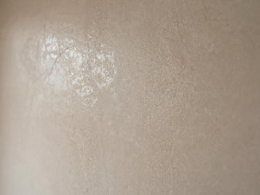 Polished Venetian plaster wall texture in natural stone color, reflecting soft light with subtle veining, extreme close-up.