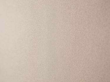 Close-up of a soft chalky limewash wall texture in a warm off-white, natural light, high detail.