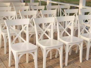 Perfectly aligned rows of wooden cross-back chairs inside an empty pavilion, soft golden hour light, clean editorial composition