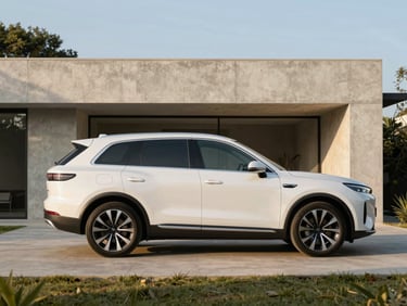 Side profile of a clean modern luxury SUV parked in the driveway of a minimalist concrete villa, warm morning light, 35mm