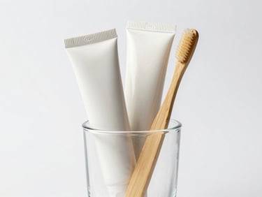 Clean cosmetic tubes and bamboo toothbrushes in a minimalist glass cup, bright high-key studio lighting