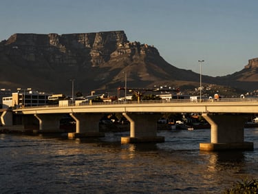 Infrastructure project, new bridge construction over a river near Cape Town, dramatic natural shadows, high-contrast.