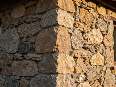 Close-up of a stone foundation corner on a mountain home, precise coursework in warm sandstone, natural morning light raking across the surface to reveal texture and tight mortar joints