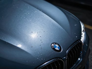 Macro shot of sharp light reflection on a freshly polished metallic dark blue BMW hood, water droplets, sleek automotive photography