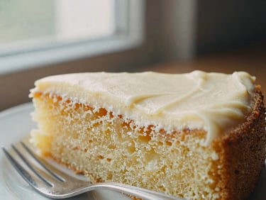 Close-up of a slice of lemon drizzle cake with a fork, soft side-lit window daylight, rich cream tones, shallow depth of field, 35mm film