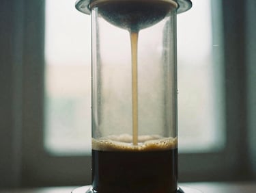 Close-up of an Aeropress brewing coffee, showing the plunger and dark liquid, soft side-lit window daylight, rich espresso and cream tones, shallow depth of field, 35mm film