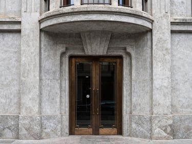 Art deco building entrance in Condesa, curved concrete lines, elegant bronze details, soft daylight