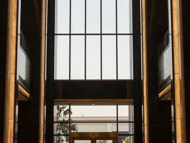 Clean, symmetrical architectural shot of a high-end corporate lobby with rich gold accents and immaculate glass panels.