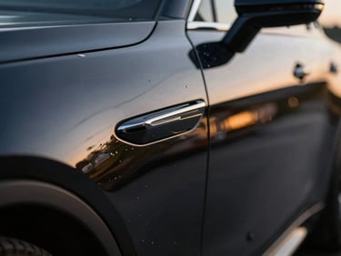 Close-up of a dark car panel perfectly reflecting a blurred environment, showing extreme wet-look depth and shine, studio lighting, 85mm