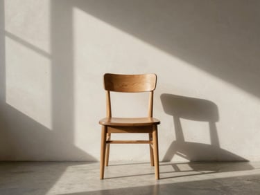 A quiet, sun-drenched minimalist room with a single wooden chair, soft shadows stretching across a raw plaster wall.