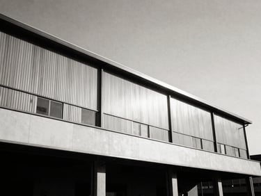 Architectural low-angle shot of a clean, modern manufacturing plant facade, high contrast black and white format