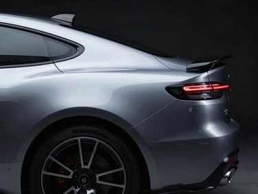Sleek rear profile of a metallic silver performance car showing rich reflections, dark studio environment.