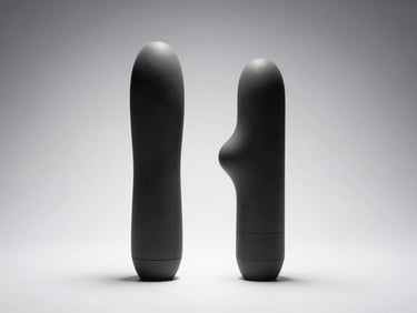 Straight-on studio shot of two compact vibrators laid flat on a clean white surface, one with a curved tip, strong overhead directional lighting revealing silicone texture and material sheen, neutral grey-white background, no people, no staging