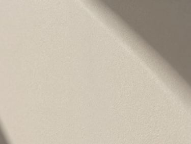 Extreme close-up of matte bone-white mineral paint texture, fine chalky grain, soft directional daylight
