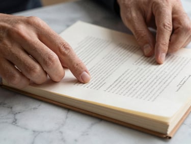 Extreme close-up of hands turning pages of a property registry document on a marble surface, neutral studio light, fine paper grain visible