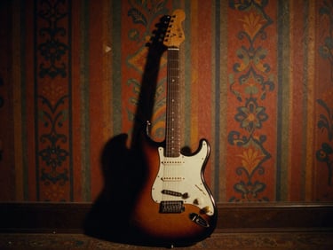 Cinematic film still, low-key warm lighting, a vintage electric guitar resting against a colorful patterned wall, 35mm grain.