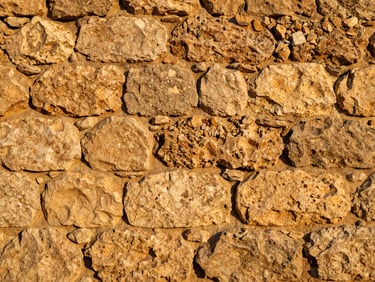 Close-up of historic Mallorcan dry stone wall, warm golden-hour light, rustic masonry detail, tactile texture.
