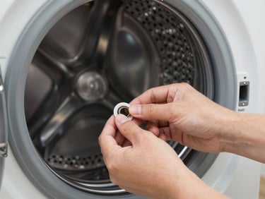 Close-up of clean hands replacing a drum seal on a premium washing machine, bright high-CRI white work light.