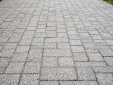 Same stone pavement at German residential property after pressure washing, joints clean and pale, surface dry and uniform, overcast daylight showing crisp restored texture