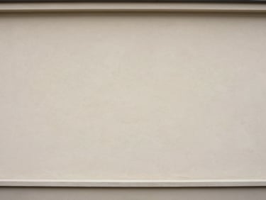 Same building facade after professional cleaning, rendered plaster surface restored to original light tone, overcast daylight showing uniform clean finish across full wall