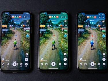 Extreme close-up overhead flatlay of three Android phones side by side displaying a fast-paced game interface, cool studio strobe lighting, dark matte surface, no reflections