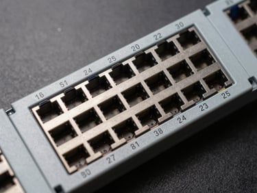 Overhead close-up of a 24-port Cat6A shielded patch panel on a neutral dark surface, numbered ports in sharp focus, consistent studio lighting, no text overlays