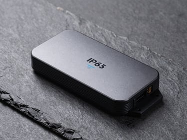 Three-quarter flat-lay of an outdoor IP67 Wi-Fi 6E access point on a neutral slate surface, weatherproof housing and mount bracket detail visible, controlled studio strobe, minimal shadows