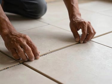 Detail shot of freshly laid ceramic floor tiles, grout lines perfectly aligned, craftsman's hand pressing the final tile into place, warm indoor daylight, Nganjuk home interior