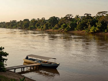 Wide environmental shot of the Amazon river bend from a riverbank, a small motorboat docked at a wooden pier, late afternoon golden light reflecting off water, dense jungle treeline stretching across the full background horizon