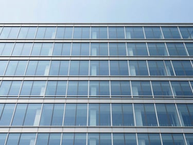 Wide-angle architectural shot of a structural glass facade, crisp blue sky reflection, clean minimalist composition, high contrast