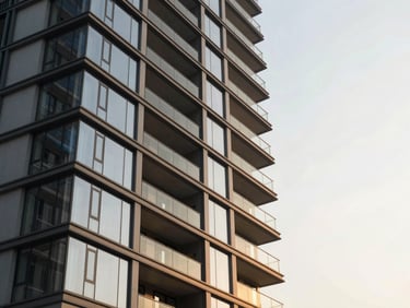 High-contrast architectural shot of a modern residential tower in Kharadi at golden hour, low angle looking up, glass and steel facade reflecting the warm sky.