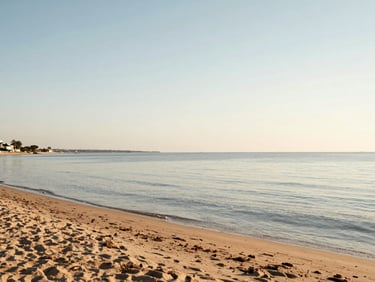 Wide panoramic shot of a quiet sandy beach at the Mar Menor lagoon during soft golden hour, calm shallow water, natural Mediterranean light