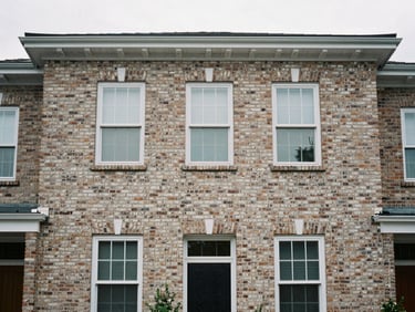 Straight-on architectural framing of a classic brick residential facade, natural overcast daylight, desaturated neutral tones, sharp focus, 35mm
