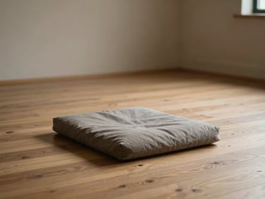 Quiet environmental shot of a minimalist studio space with warm diffused light, a single meditation cushion on a clean timber floor.