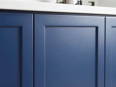 Close-up of a modern kitchen cabinet door with a flawless, high-gloss navy blue finish, showing sharp reflections and pristine edges.