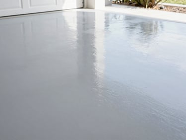 An immaculate, high-gloss gray epoxy garage floor reflecting overhead LED lighting, showing a perfectly seamless, clean surface.